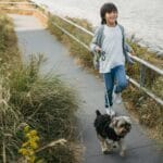 Chłopiec spaceruje z psem nad malowniczą ścieżką nad Wartą w Śremie