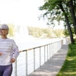 Starsza kobieta biegnie ścieżką nad Prosną w słoneczny dzień