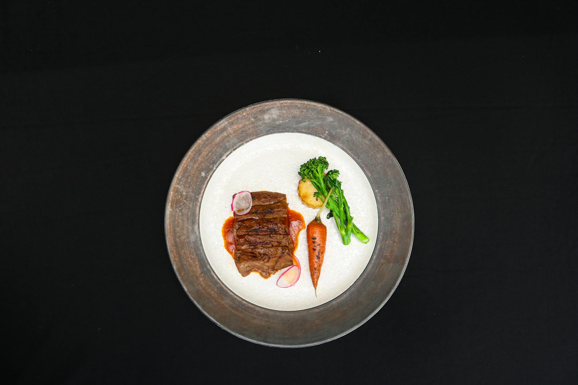 Eleganckie danie stekowe z warzywami na czarnym tle