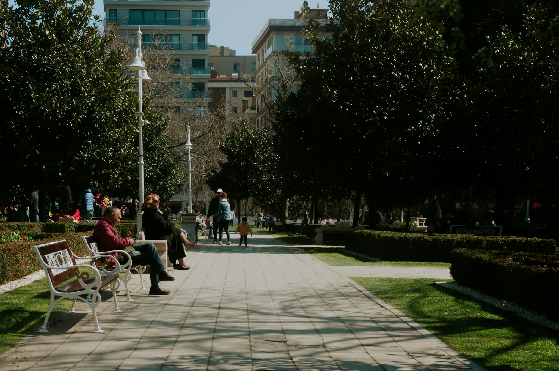 Ludzie spacerują i odpoczywają w słonecznym parku miejskim