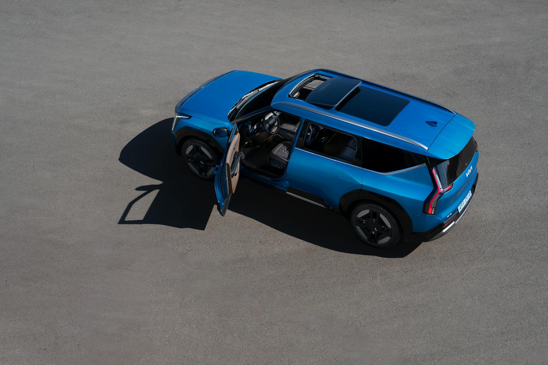 Niebieski SUV z otwartymi drzwiami zaparkowany na pustym asfalcie