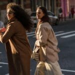 Przyjaciele w eleganckich płaszczach przechodzą przez przejście dla pieszych