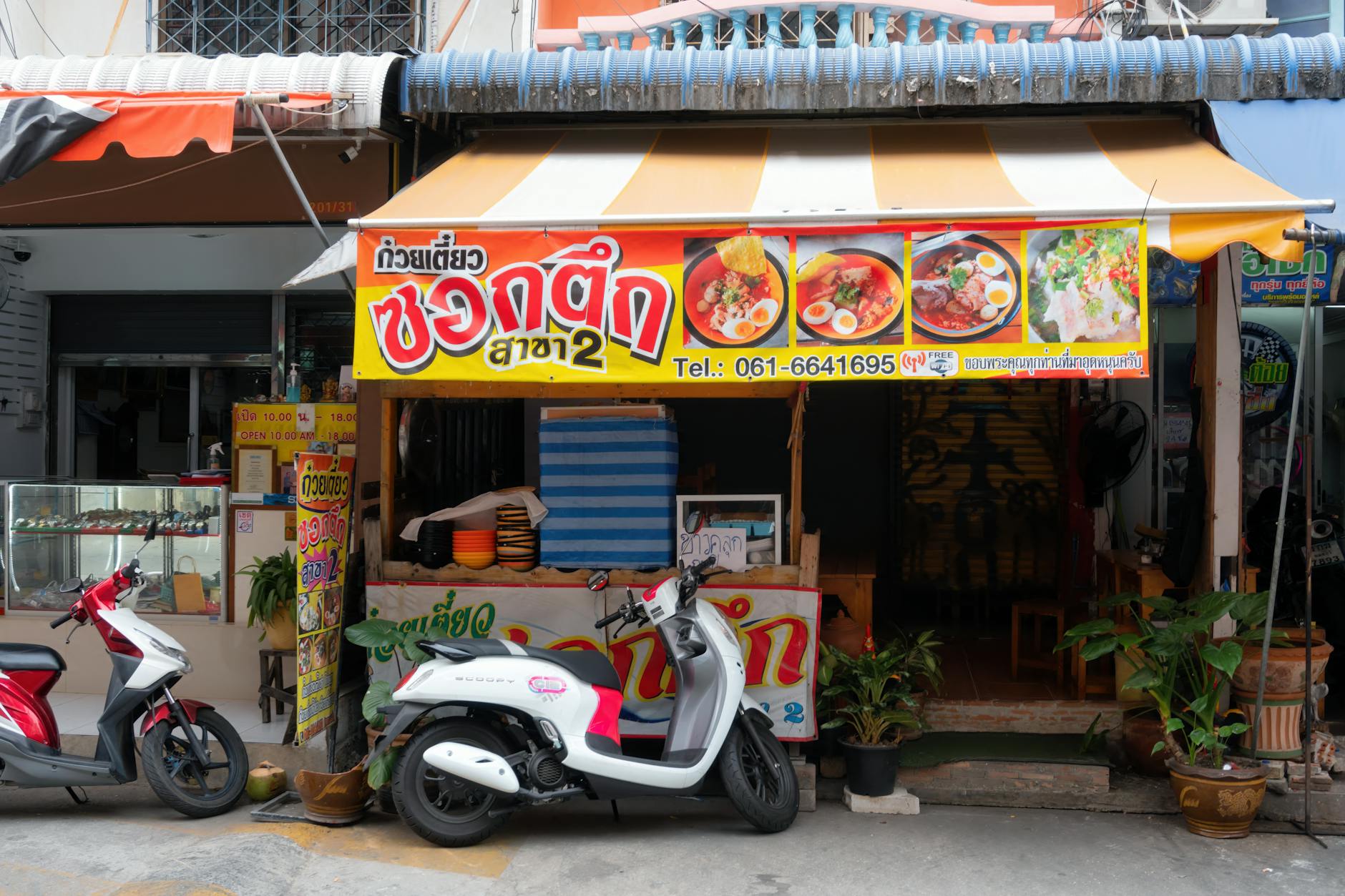 Ulica z tanim barem z makaronem i skuterami przed lokalem