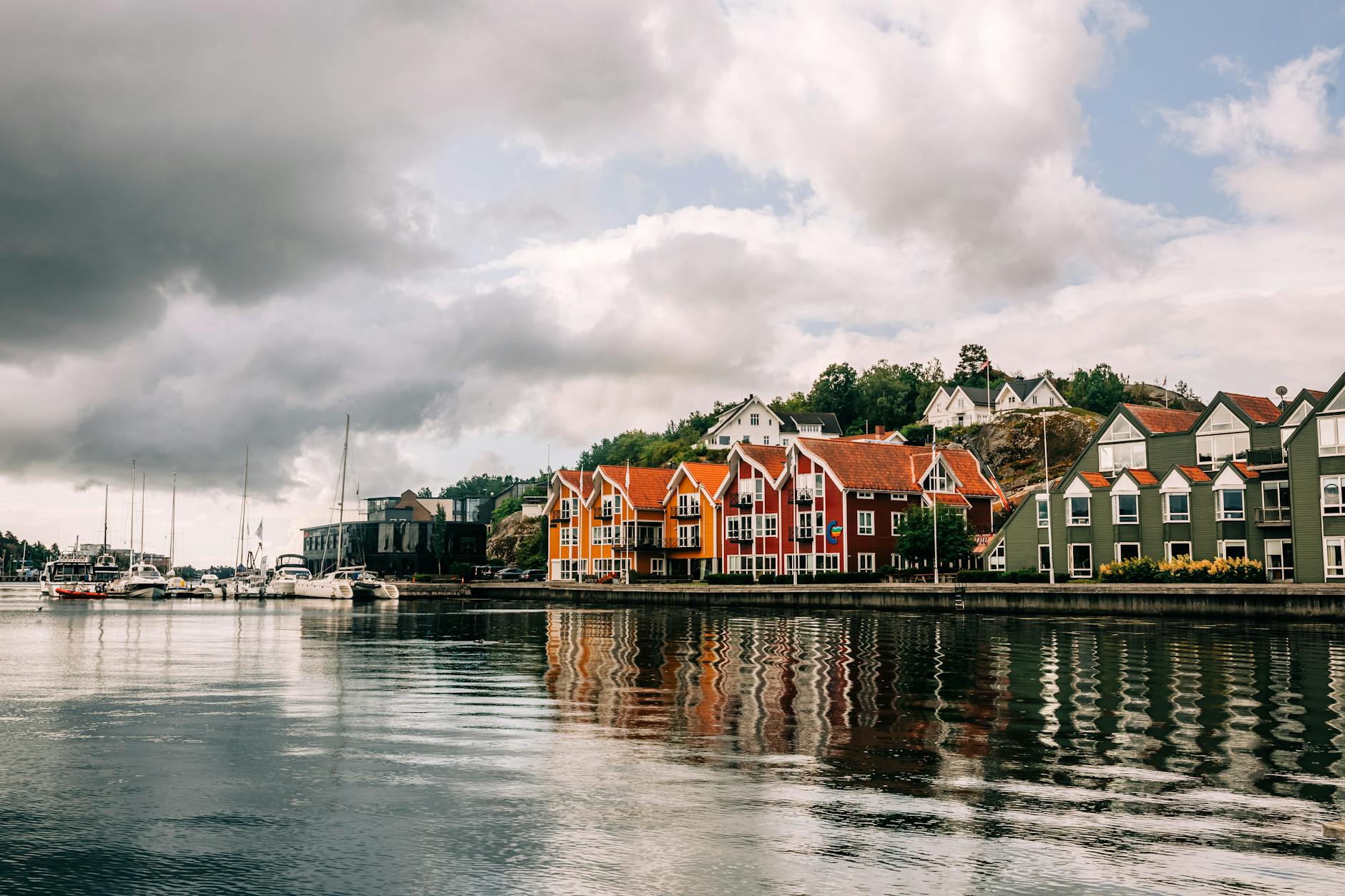 Kolorowe domy nad spokojną wodą przy burzowym niebie