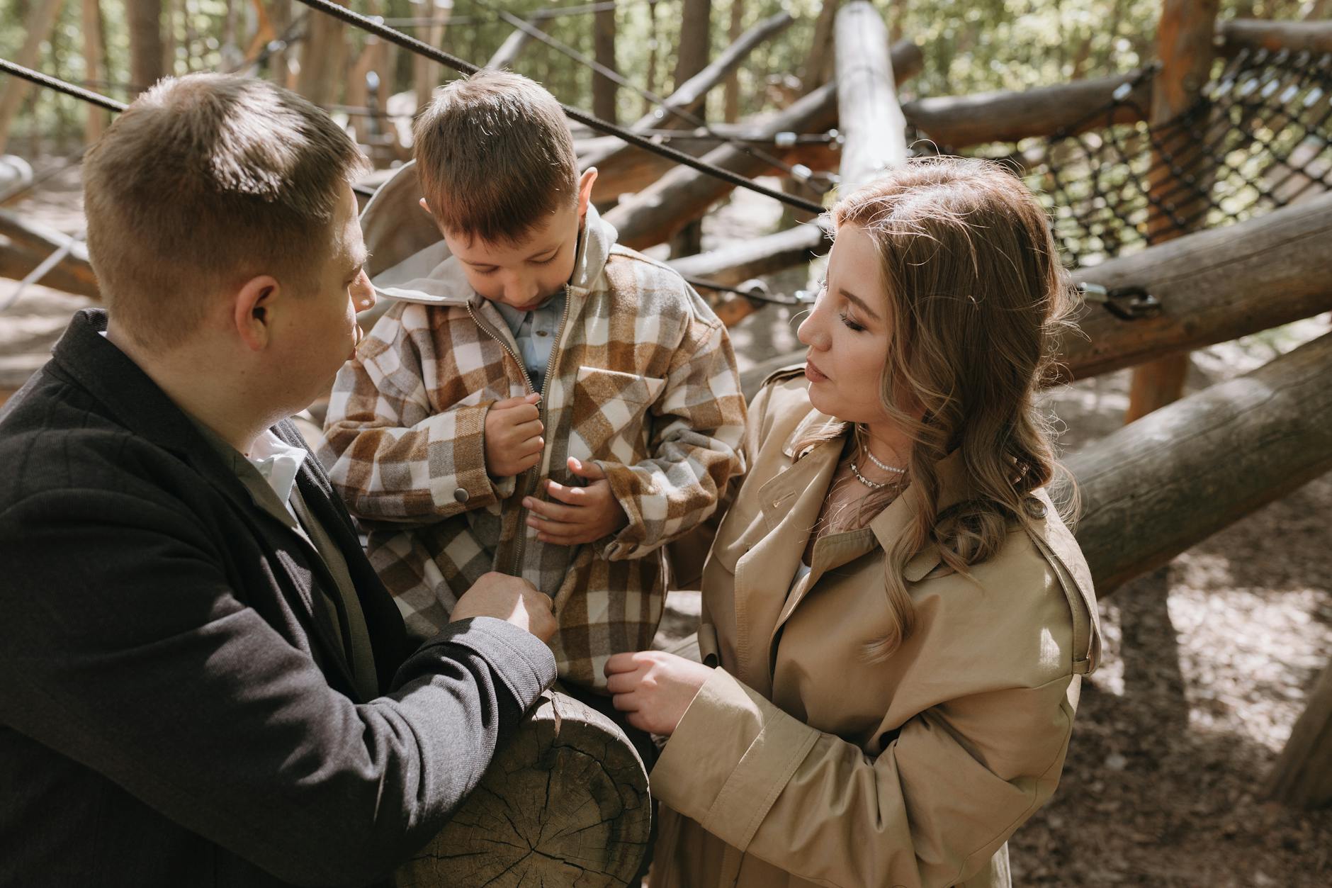 Rodzice bawią się z dzieckiem na leśnym placu zabaw w słońcu