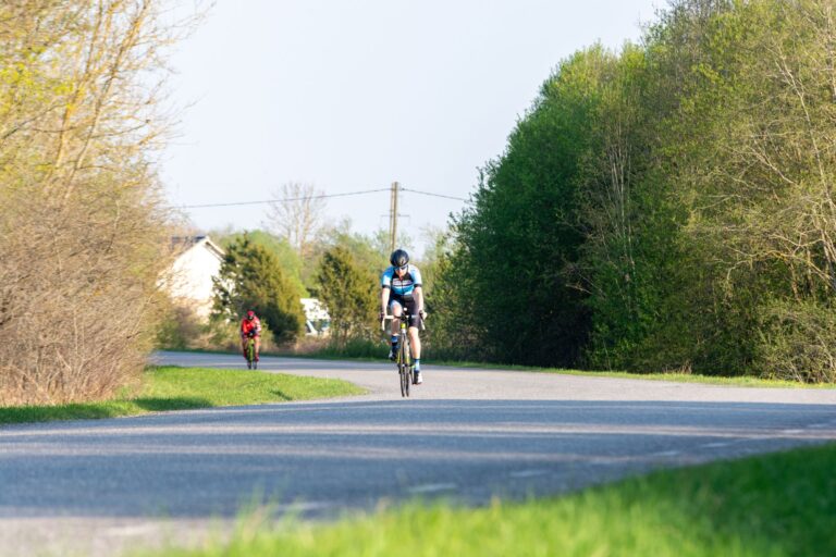 Rowerzyści jadący słoneczną wiejską drogą wśród zieleni